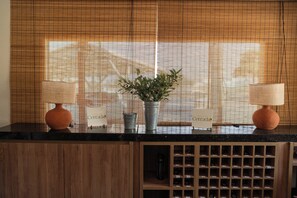A hotel reception desk with a potted plant, two lamps, and a wine rack. - Hotel do Cerrado (Luís Eduardo Magalhães)