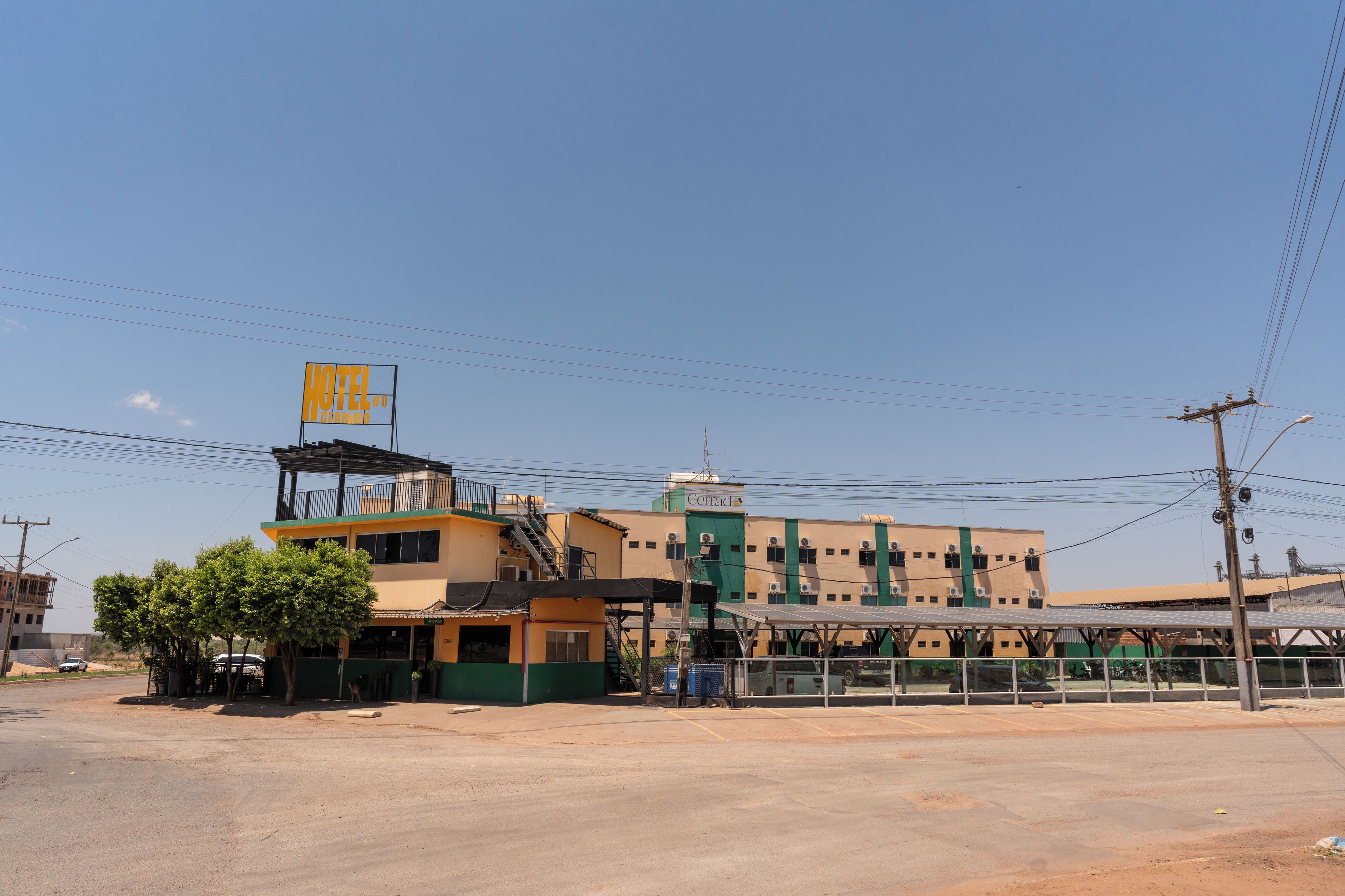 A hotel with a prominent yellow sign, a green and yellow facade, and a parking area in front.