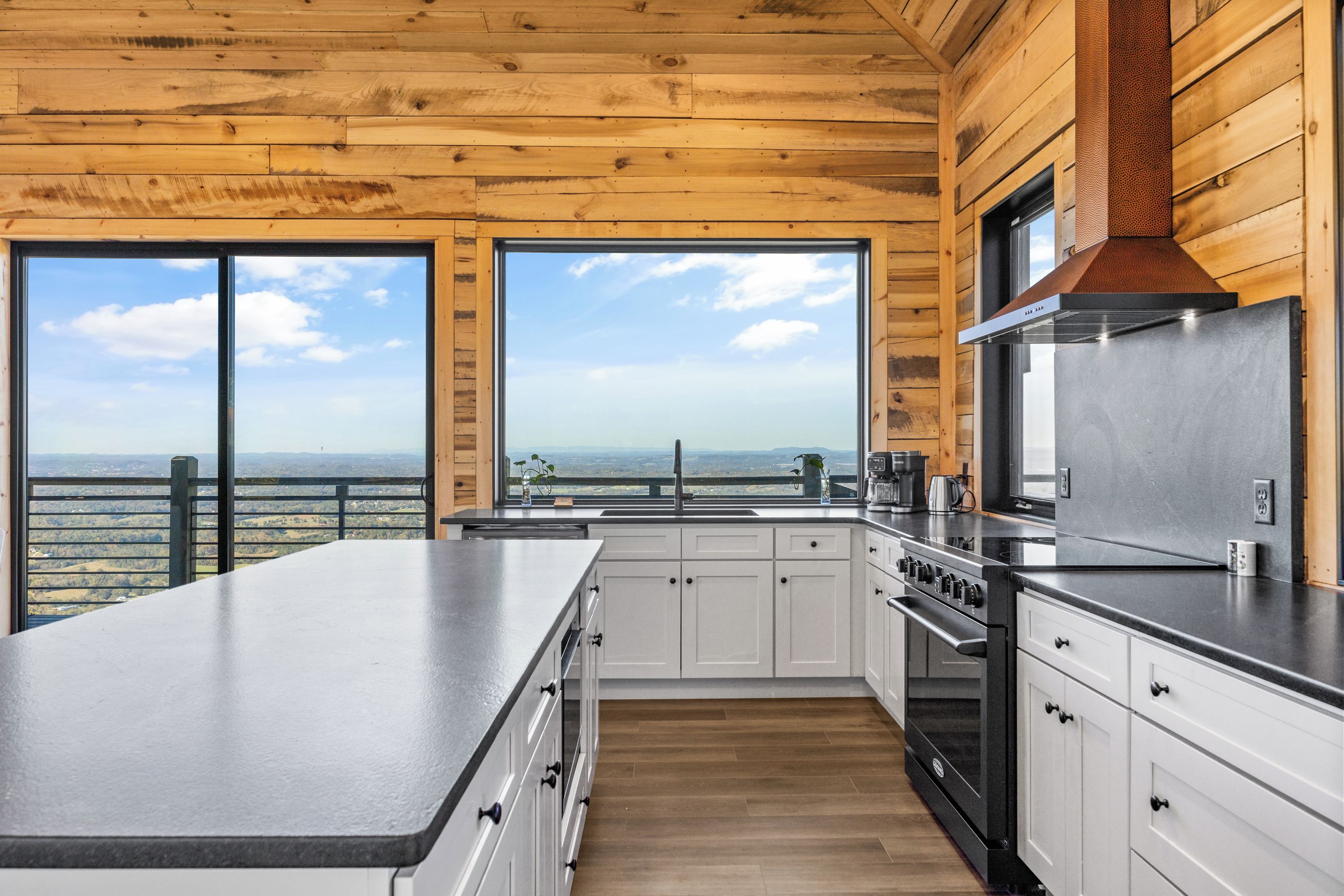 A modern kitchen with a large island, stainless steel appliances, and a view of the countryside.