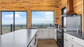 A modern kitchen with a large island, stainless steel appliances, and a view of the countryside.