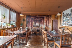 A restaurant with wooden interiors, long tables, and chairs.