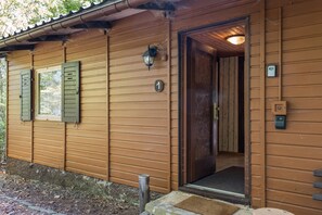 A wooden building with a door, a window with shutters, and a number plate.