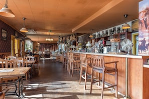 A bar area with wooden furniture and a variety of items on the shelves.
