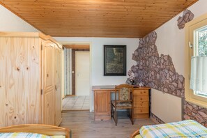 A room with wooden furniture, a desk, a chair, and a bed with a checkered bedspread.