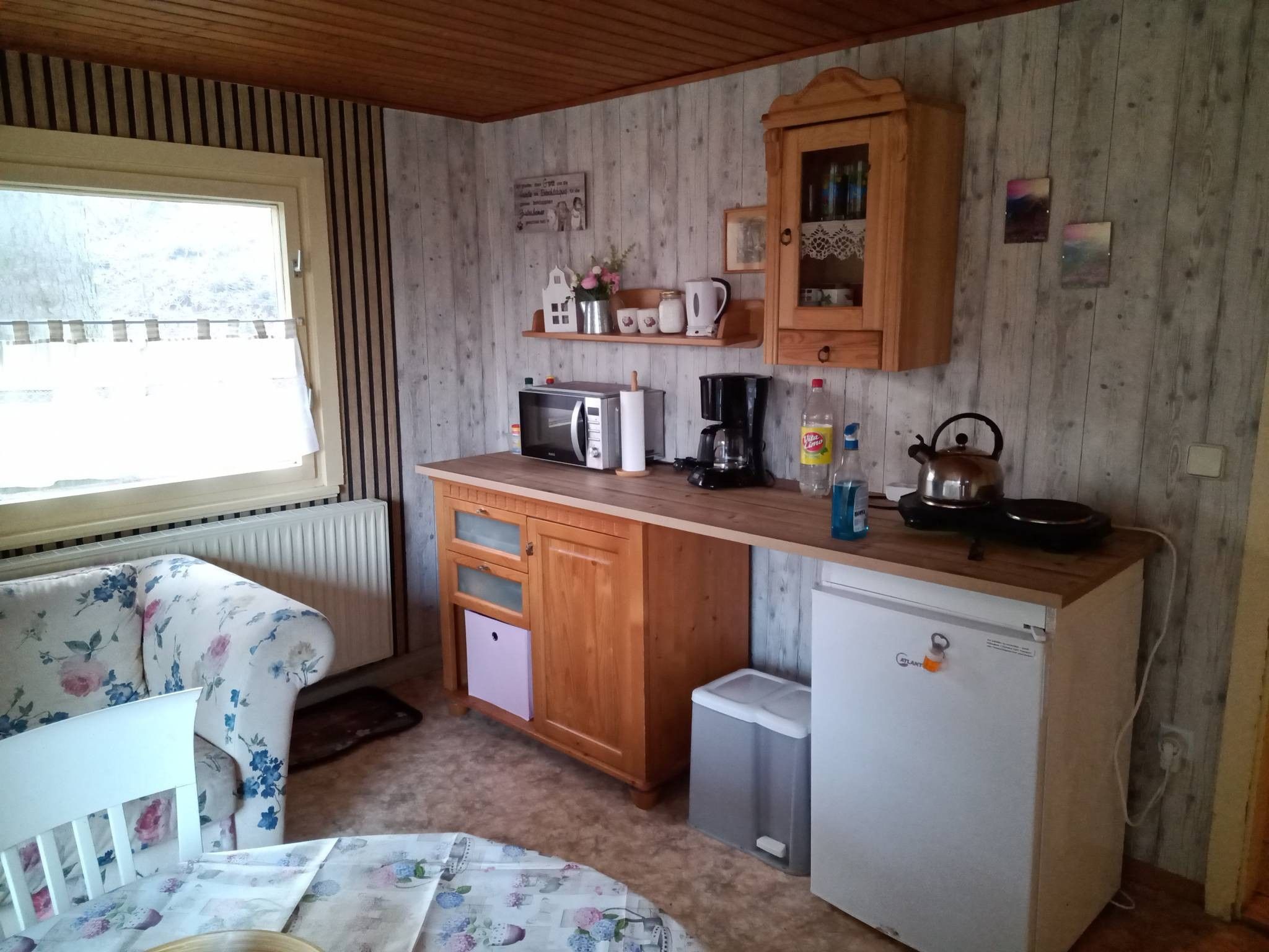 Eine kleine Küche mit Mikrowelle, Kaffeemaschine, Wasserkocher und Kühlschrank.