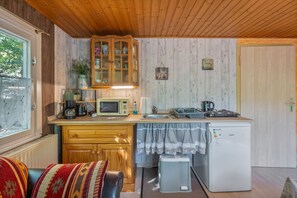 Eine kompakte Küche mit Holzschränken, einer Mikrowelle, einem Spülbecken und einem kleinen Kühlschrank.