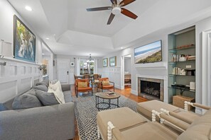 A spacious living room with a fireplace, a dining area, and a view of the ocean. - Kiawah Exclusives | 33 Inlet Cove (Kiawah Island)