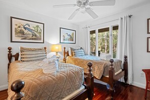 A hotel room with two beds, a ceiling fan, and artwork on the walls. - Kiawah Exclusives | 33 Inlet Cove (Kiawah Island)