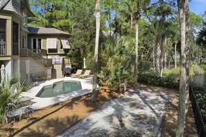 A house with a swimming pool, outdoor seating, and a surrounding wooded area. - Kiawah Exclusives | 50 Salt Cedar (Kiawah Island)