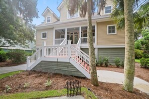 Ein zweistöckiges Haus mit Veranda, Treppe und einem kleinen Garten.