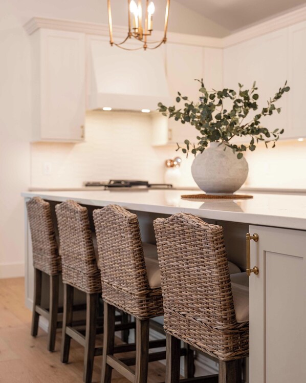 A kitchen with a white countertop, a hanging light fixture, and a potted plant.
