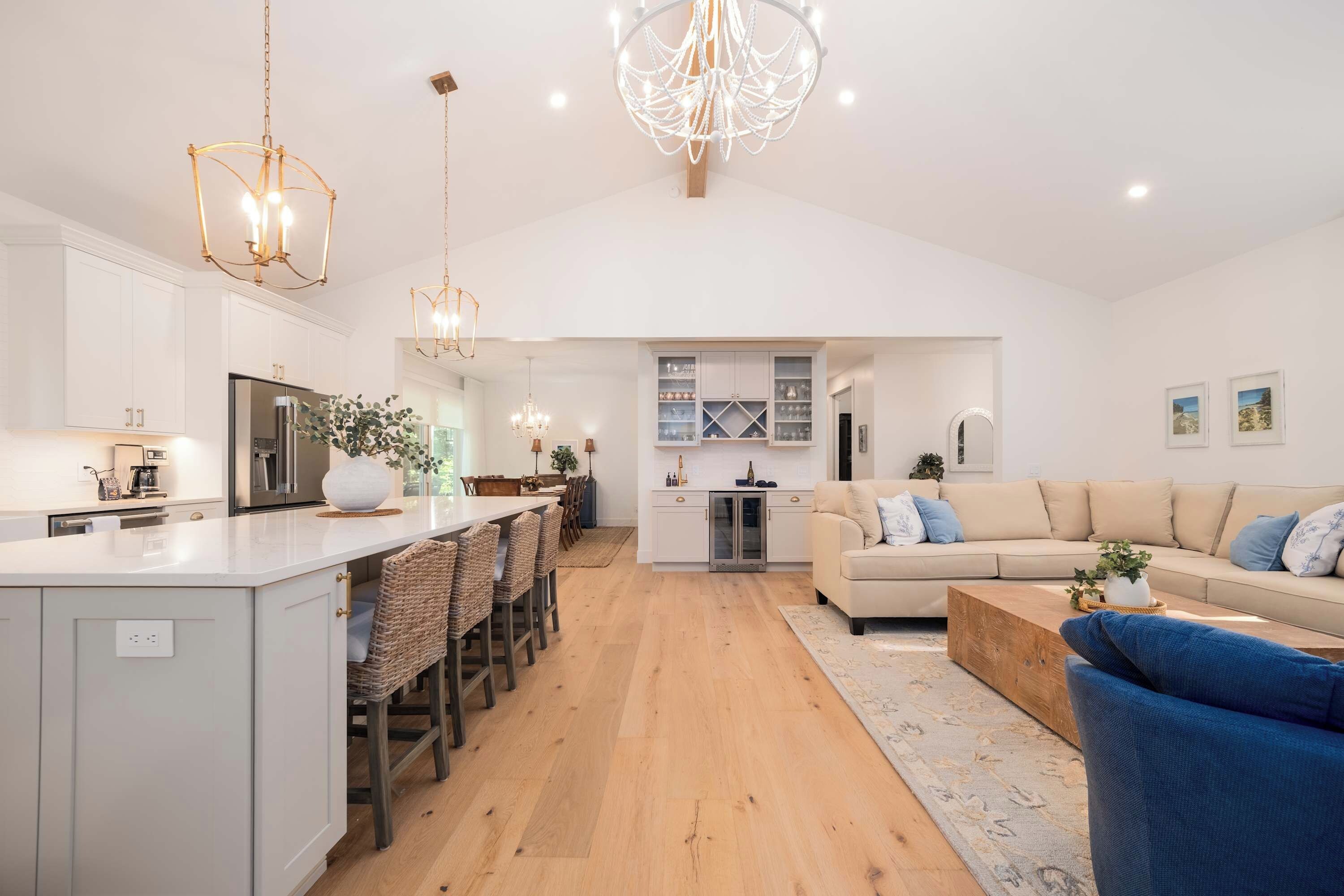 A modern kitchen with a central island, bar seating, and a dining area with a sofa and coffee table.
