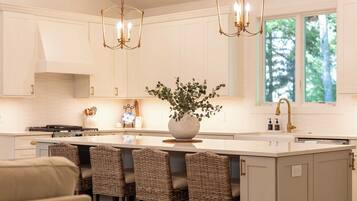 Una cocina moderna con una isla central, taburetes de bar e iluminación colgante.