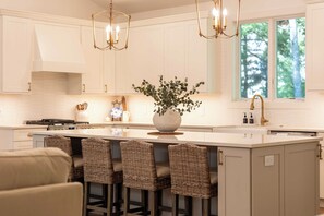 A modern kitchen with a central island, bar stools, and pendant lighting.