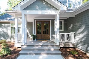 A house with a front porch, a double door, and a small window to the right.