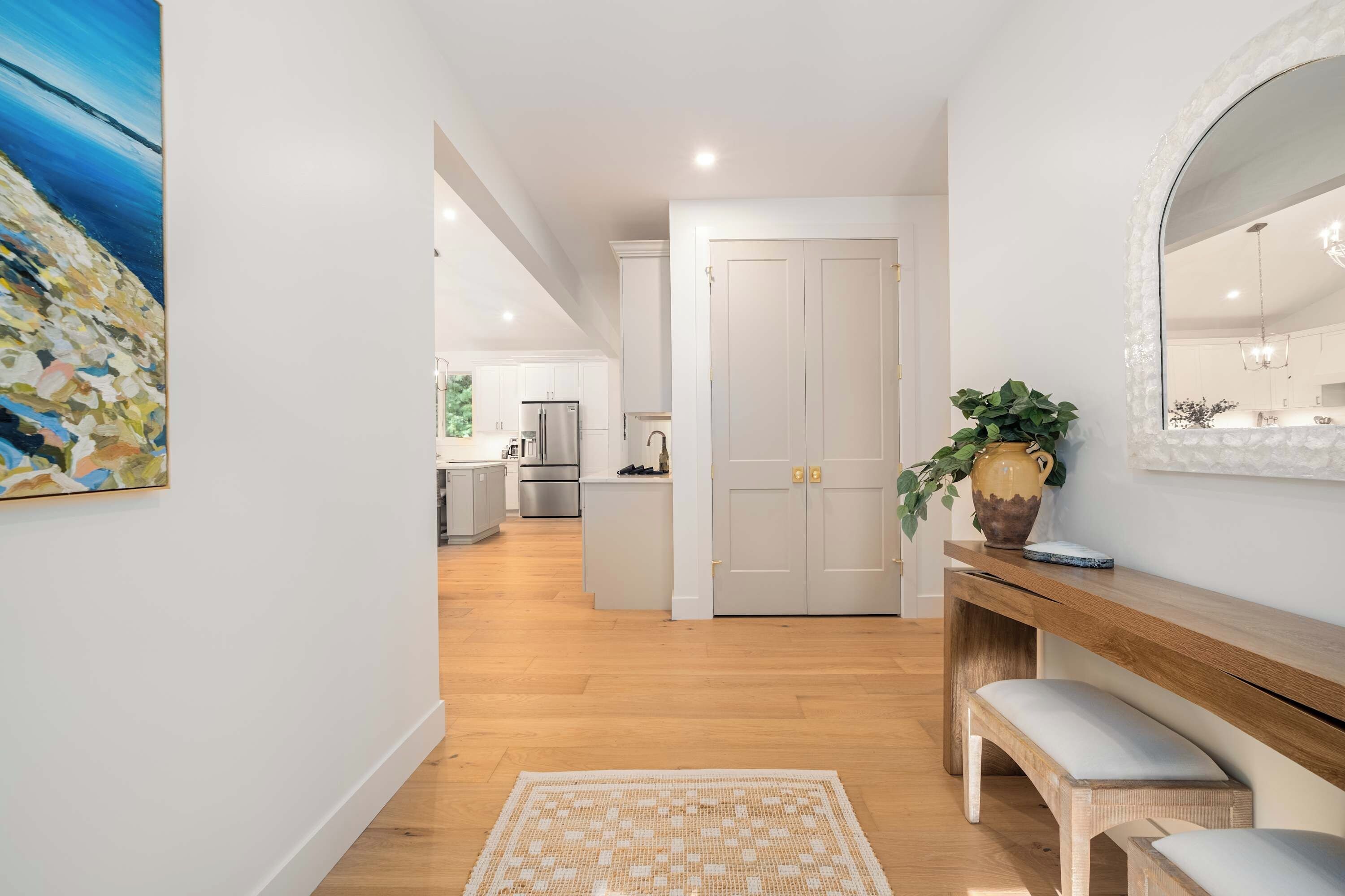 Una cocina moderna con armarios blancos, electrodomésticos de acero inoxidable y piso de madera.