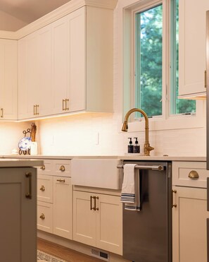 A kitchen with white cabinets, a stainless steel refrigerator, and a window above the sink.