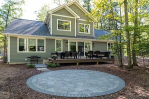 A two-story house with a covered patio and a circular stone patio in front.
