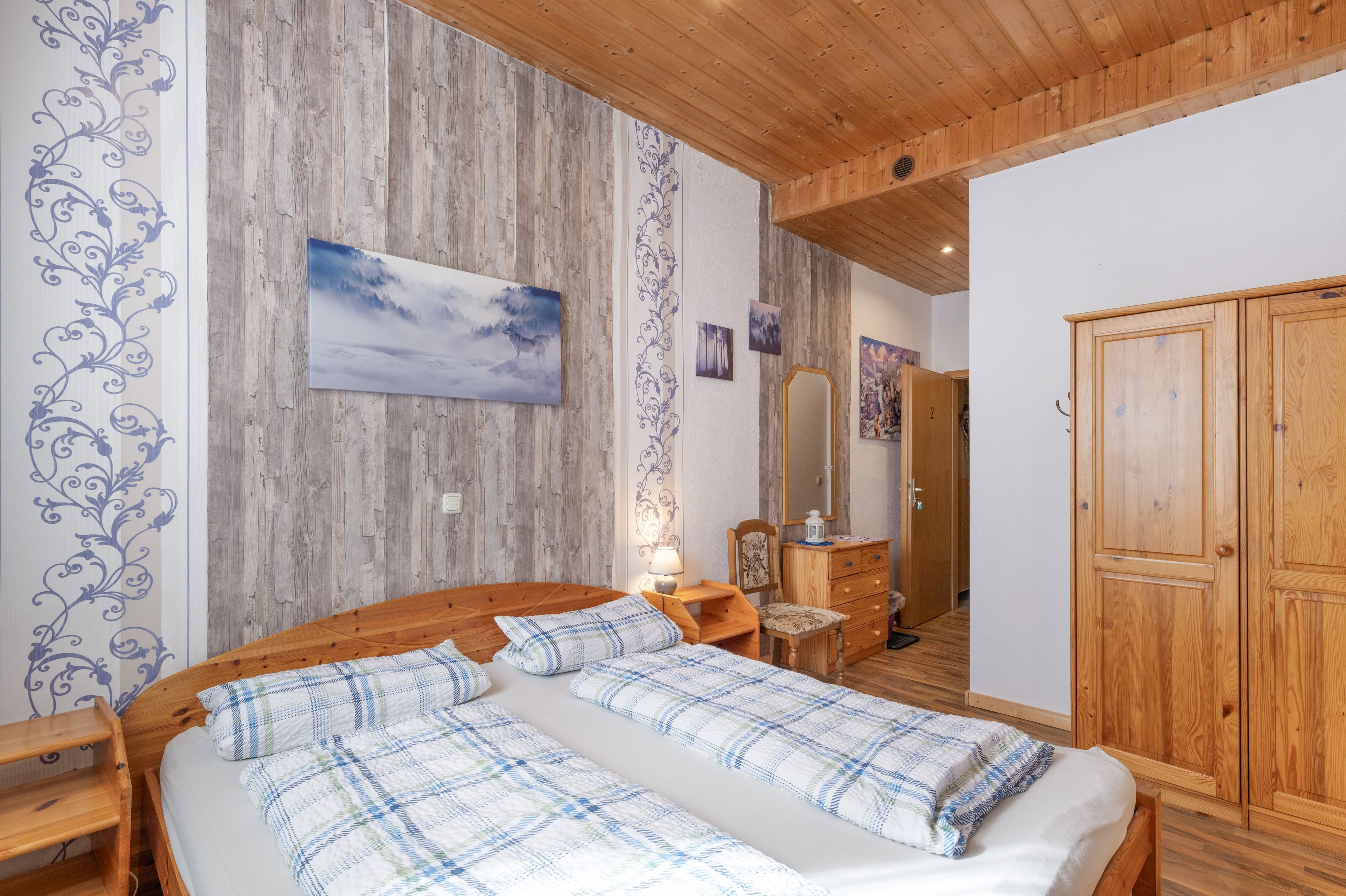 A bedroom with a wooden bed, a nightstand, a dresser, and a mirror.