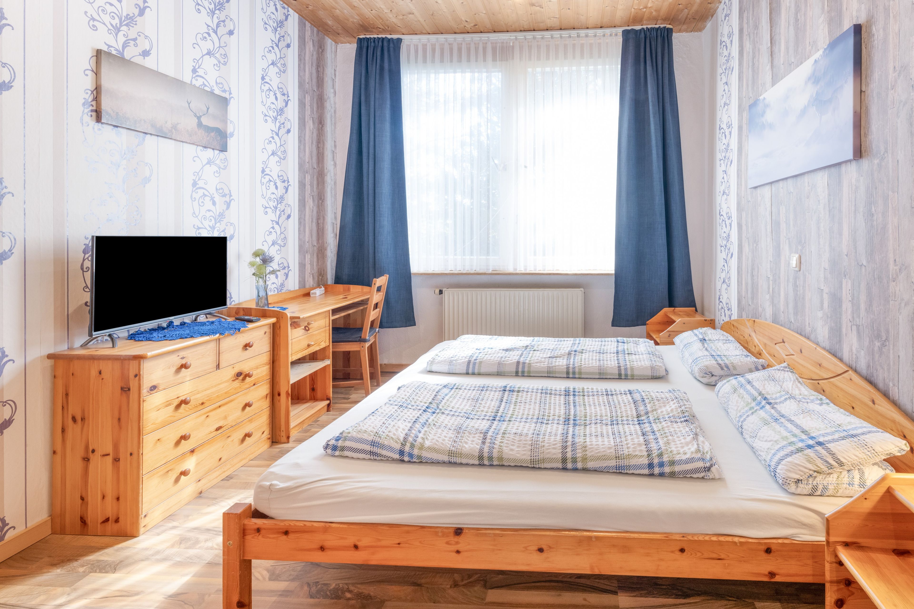 Un dormitorio con cama de madera, un escritorio, televisor y radiador.