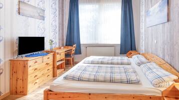 Un dormitorio con cama de madera, un escritorio, televisor y radiador.