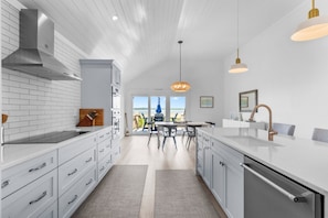A modern kitchen with white cabinetry, a central island, and a view to the outside. - Seabrook Exclusives | 1354 Pelican Watch (Seabrook Island)