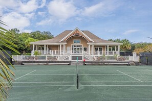 Camp de tennis amb una casa al fons.