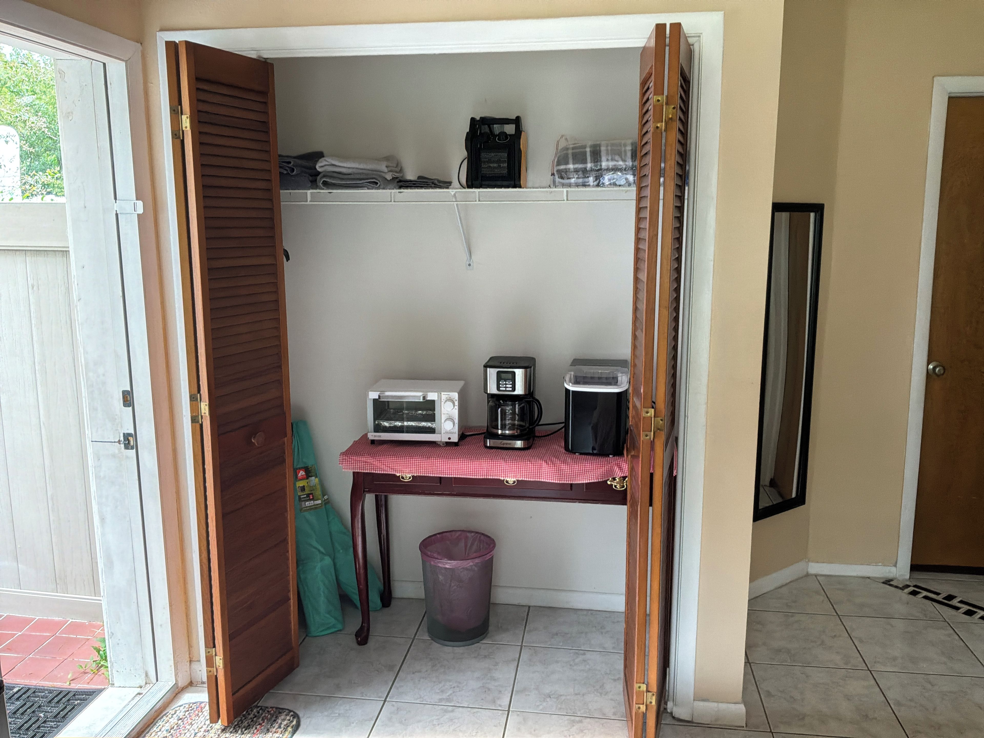 A compact kitchenette with a toaster, coffee maker, and a small refrigerator.