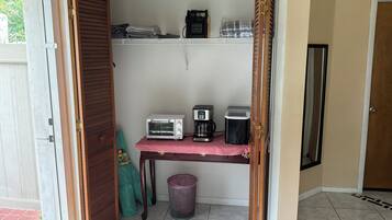 A compact kitchenette with a toaster, coffee maker, and a small refrigerator.