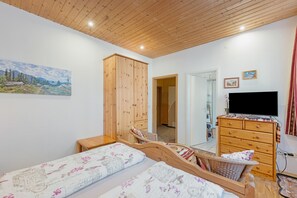 A bedroom with a bed, a wooden wardrobe, a television, and a painting on the wall. - Room 'Doppelzimmer 1' with Wi-Fi (Tambach-Dietharz)
