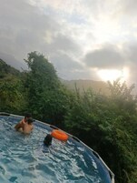 Piscina rodeada de abundante vegetación y vistas a colinas distantes.