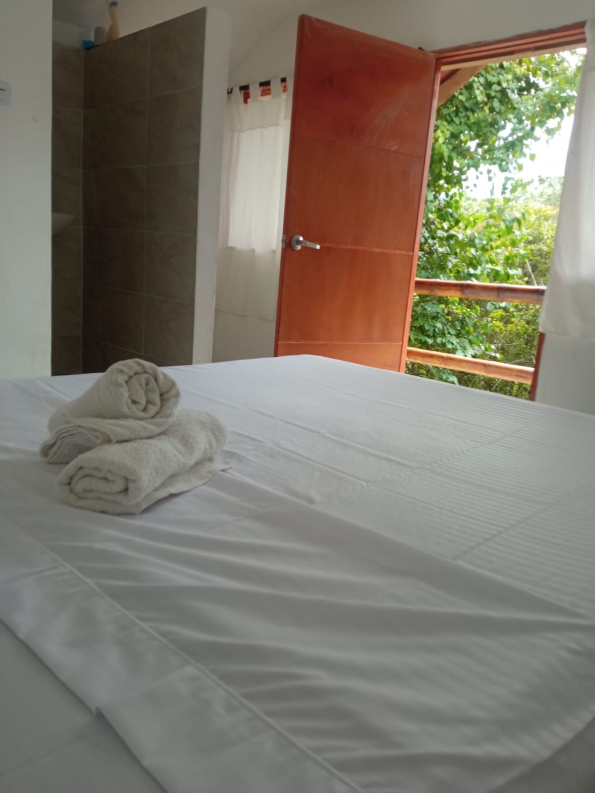 Quarto de hotel com cama, banheiro e vista pela porta aberta.