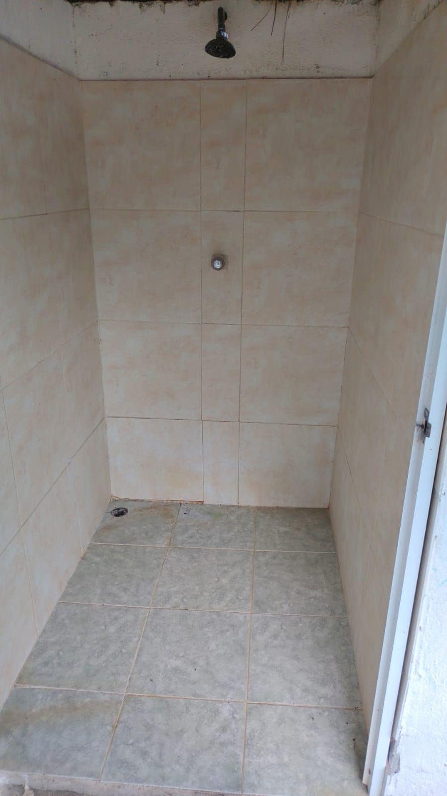 A small, tiled shower room with a single showerhead.