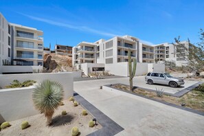 Una zona residencial moderna con edificios de varios pisos, un área de estacionamiento y vegetación desértica.