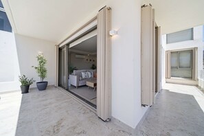 An open sliding door leading to a living area with a sofa and a coffee table. - Brand New Pet-friendly Condo - Private Pool (Cabo San Lucas)