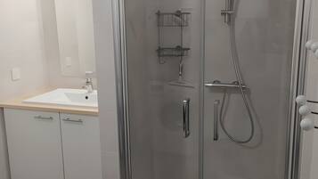 Une salle de bain moderne avec une douche à parois de verre, un lavabo avec un miroir et des toilettes.