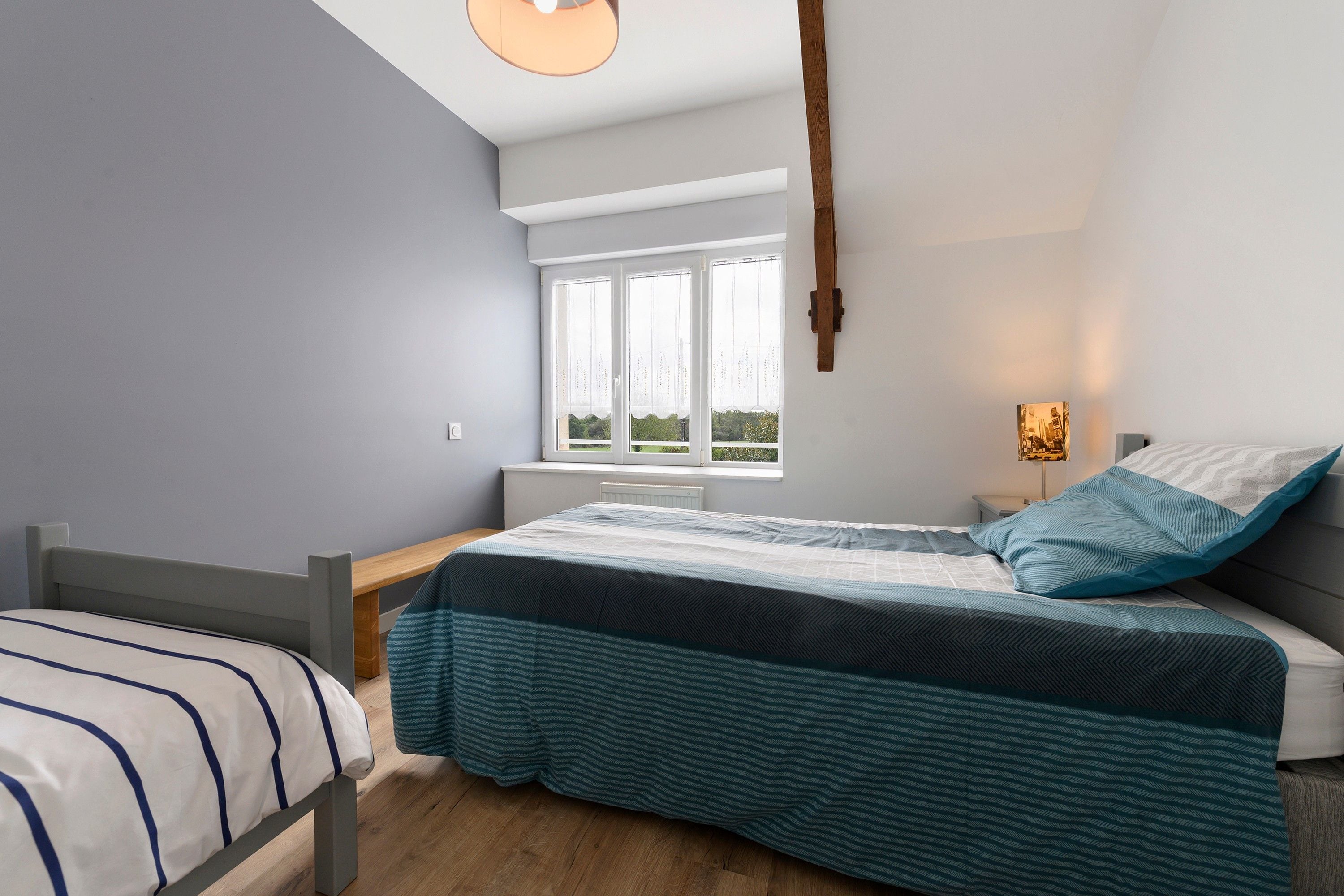 A bedroom with a bed, a window, a bedside table, and a lamp.