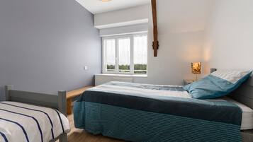 A bedroom with a bed, a window, a bedside table, and a lamp.