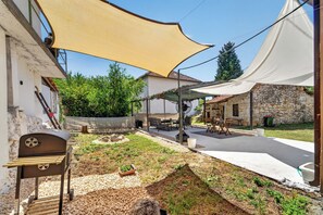 A patio area with outdoor furniture, a barbecue grill, and a stone wall.