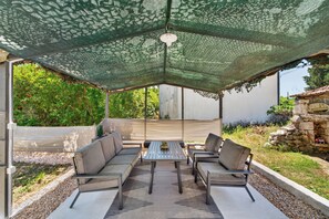 An outdoor patio with a table and chairs, a green canopy, and a stone wall. - Traditional Stone House Near St. James Church, Private Yard (Međugorje)
