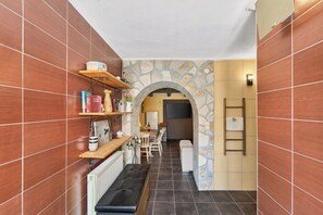 A narrow hallway with wooden shelves, a stone wall, and a bench. - Traditional Stone House Near St. James Church, Private Yard (Međugorje)