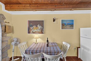 A dining area with a table set for two, a lamp, and a bottle of wine. - Traditional Stone House Near St. James Church, Private Yard (Međugorje)