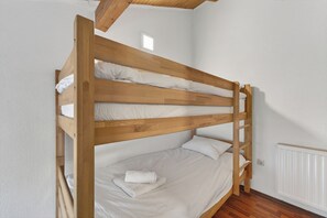 Uma cama beliche com estrutura de madeira e roupa de cama branca.