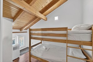 A bunk bed in a room with a sloped ceiling and a window.
