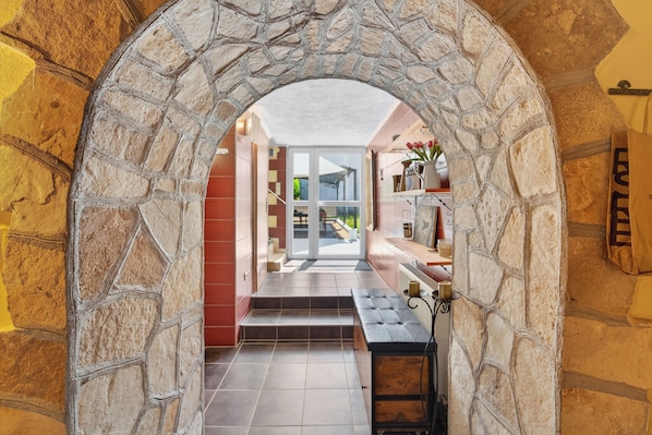 A stone archway leading to a modern kitchen with a view of a garden.