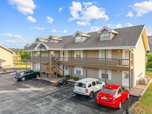 A multi-story motel with a covered parking area, a staircase, and a view of the surrounding landscape. - Fall Creek Condo | Minutes to Strip, SDC & Lakes (Branson)