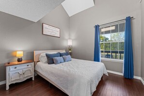 A bedroom with a bed, a nightstand, a lamp, a window with curtains, and a motivational quote on the wall. - Fall Creek Condo | Minutes to Strip, SDC & Lakes (Branson)