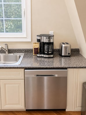 A kitchen with a stainless steel dishwasher, a coffee maker, and a toaster on a granite countertop. - 4 Bedroom Fleetwood Gem-City Access, Suburban Comfort (Mount Vernon)