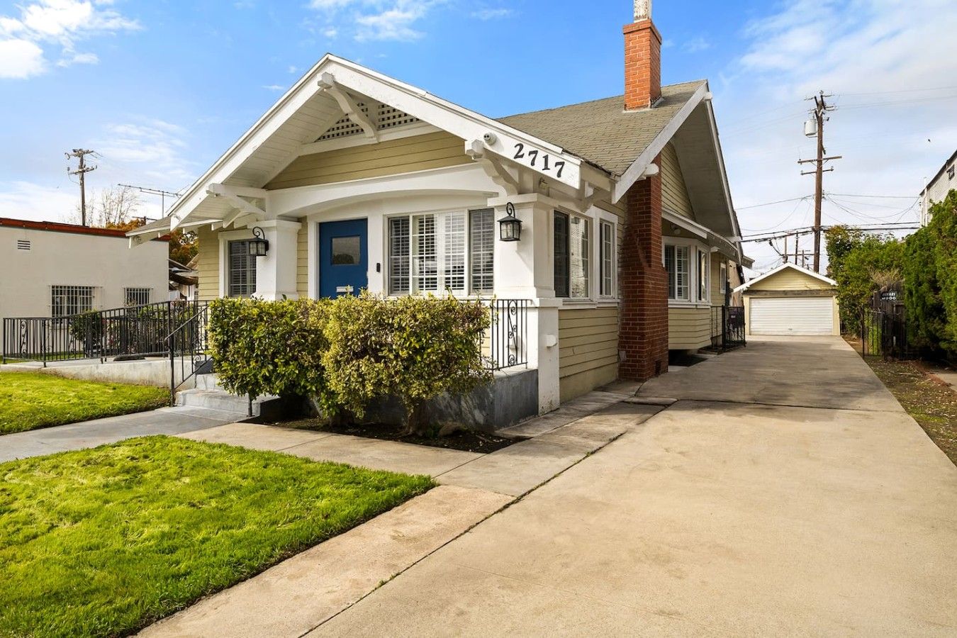 A single-story house with a front porch, a blue door, and a number '2717' on the side.