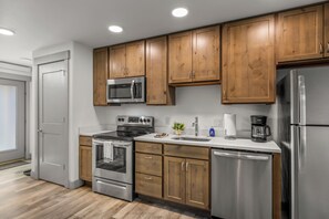 A modern kitchen with wooden cabinets, stainless steel appliances, and a built-in oven. - Quaint Riverfront Property Close to the Resort! Pet Friendly. (Steamboat Springs)